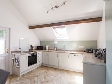 A kitchen with white cabinets wooden countertops a skylight and various appliances at Stabal Bach in Criccieth