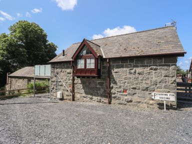 A stone building with a slate roof and a sign indicating parking for visitors at Stabal Bach in Criccieth