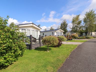 A pathway next to small houses with decks and garden plants at 41 Grandmas Cottage South Lakeland Leisure Village near Carnforth