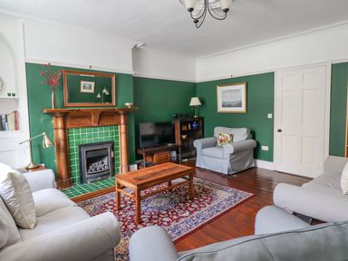 A living room with green walls a wooden fireplace a wooden coffee table two sofas and an armchair at Victoria House in Alnwick