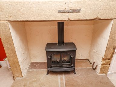 A black wood-burning stove inside a stone fireplace at Victoria House in Alnwick