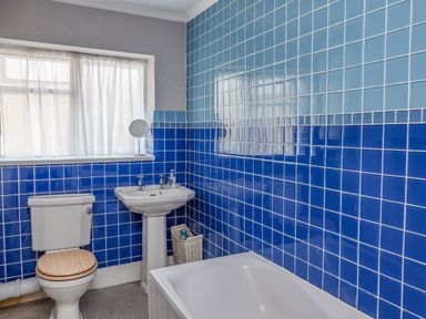 A bathroom with a toilet, pedestal sink, bathtub, and blue tiled walls at Victoria House in Alnwick
