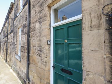 A green front door with a letterbox and number 17 on a stone building at Victoria House in Alnwick