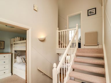 A carpeted staircase with white railing and a bunk bedroom visible to the left at Cullernose Cottage Newton-by-the-Sea near Embleton