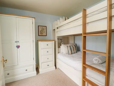 A bedroom with bunk beds a wardrobe and a chest of drawers at Cullernose Cottage Newton-by-the-Sea near Embleton