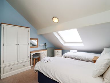 A bedroom with two single beds under a skylight and white wooden furniture at Cullernose Cottage Newton-by-the-Sea near Embleton