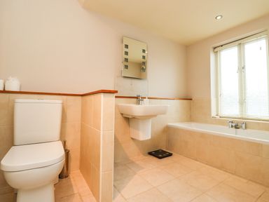 A bathroom with a toilet sink bathtub window and a scale at Cullernose Cottage Newton-by-the-Sea near Embleton