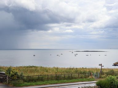 A coastal view with boats on the water and a grassy area in the foreground at Cullernose Cottage Newton-by-the-Sea near Embleton