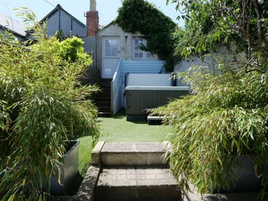 A backyard with stone steps plants a hot tub and a small building at Waves End in St Ives