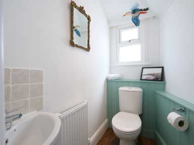 A small bathroom with a toilet sink radiator and a window at Waves End in St Ives