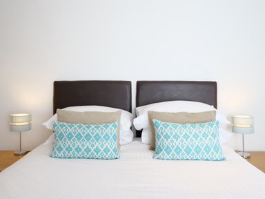 A bedroom with a double bed with patterned pillows and two bedside lamps at Waves End in St Ives