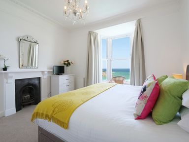 A bedroom with a bed near a window overlooking the sea at Waves End in St Ives