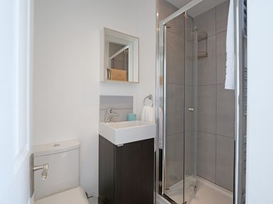 A bathroom with a toilet sink with a cabinet mirror and a glass shower enclosure at Waves End in St Ives