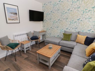 A living room with a grey corner sofa and wooden coffee table at Gwynfryn in Pen-Clawdd