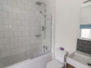 A bathroom with a bathtub shower combination toilet and sink at Gwynfryn in Pen Clawdd