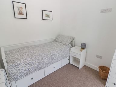A small bedroom with a single bed white bedside table lamp and framed pictures on the wall at Gwynfryn Pen Clawdd