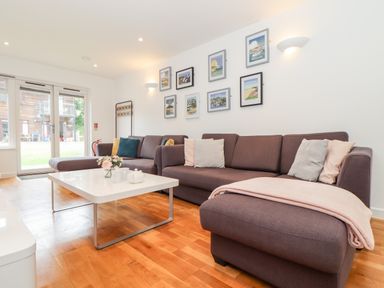 A living room with sectional sofa coffee table and framed pictures on the wall at Garras in Porthtowan