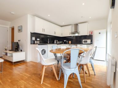 A kitchen and dining area with a round wooden table and mixed chairs at Garras in Porthtowan