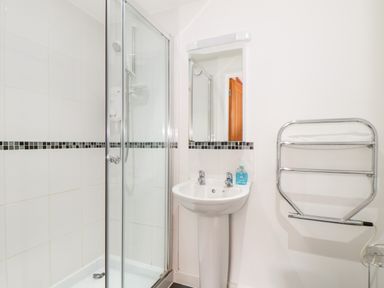 A bathroom with a shower enclosure sink mirror and towel rail at Garras in Porthtowan