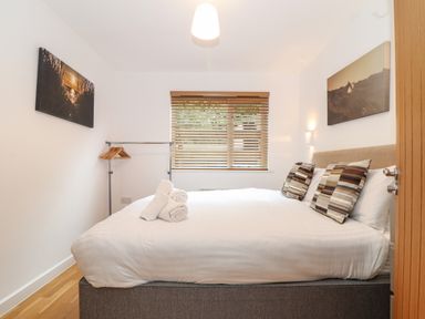 A bedroom with a bed a window with blinds and pictures on the walls at Garras in Porthtowan