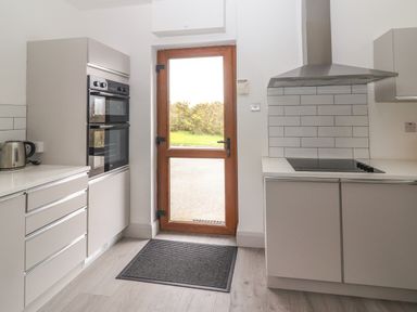 A kitchen with a wooden glass door stove hood built in oven kettle and gray cabinets at Gortnamona in Coolnaharragill Lower near Glenbeigh County Kerry