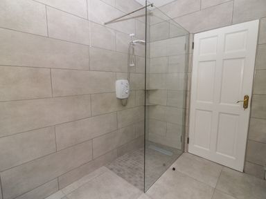 A shower area with glass partition and tiled walls next to a white door at Gortnamona in Coolnaharragill Lower near Glenbeigh County Kerry