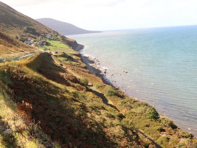 A coastal hillside with a road, houses, and vegetation beside the sea at Gortnamona in Coolnaharragill Lower near Glenbeigh County Kerry