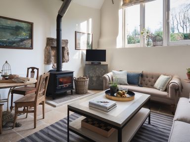 A living room with a wood stove a coffee table and a sofa at Butterwell Cottage at Collihole in Chagford