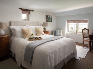 A bedroom with a large bed pillows bedside tables lamps and a window at Butterwell Cottage at Collihole in Chagford