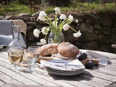 An outdoor table with bread glasses napkins plates and a vase of white flowers at Butterwell Cottage at Collihole in Chagford