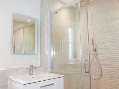 A bathroom with a sink and a mirror above it next to a glass-enclosed shower at Chynoweth House in Cubert
