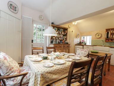 A kitchen with a dining table set with plates and teacups and wooden chairs at Chalkpit Cottage in Blewbury