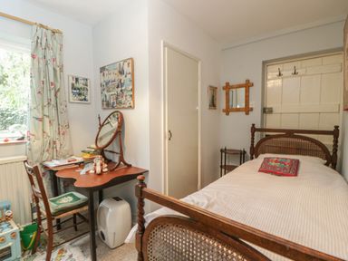 A small bedroom with a single bed a wooden desk and chair near a window at Chalkpit Cottage in Blewbury