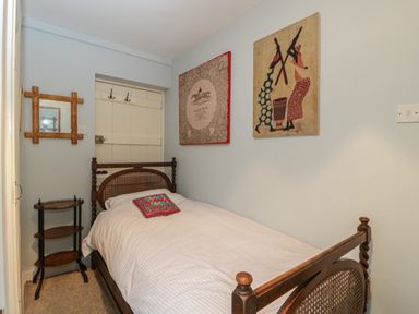 A small bedroom with a single wooden bed white bedding a small wooden side table and wall decorations at Chalkpit Cottage in Blewbury