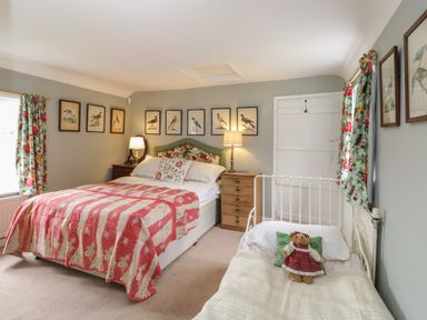 A bedroom with a double bed and a single bed with framed bird pictures on the walls at Chalkpit Cottage in Blewbury