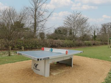 An outdoor table tennis table with two paddles on top in a park area at Chalkpit Cottage in Blewbury