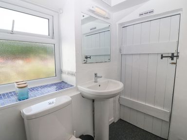 A bathroom with a toilet sink mirror and window at Pen Bonc  Llanddaniel Near Gaerwen