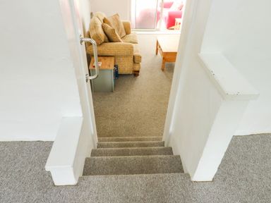 Stairs leading to a living room with a couch and coffee table at Pen Bonc Llanddaniel Near Gaerwen
