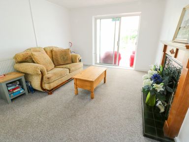 A living room with a sofa, coffee table, and fireplace at Pen Bonc Llanddaniel Near Gaerwen