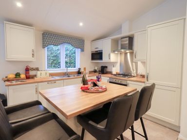 A kitchen with a wooden countertop and black bar stools at Unique Luxury Lodge, 1 Langdale, White Cross Bay near Windermere