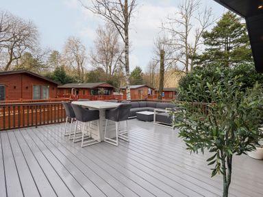 An outdoor deck with furniture and trees at Unique Luxury Lodge, 1 Langdale, White Cross Bay near Windermere