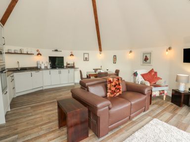 A living room with a sofa, coffee table, and kitchen area at Ty Crwn in Lampeter