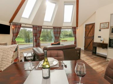 A living room with a sofa and dining setup at Ty Crwn in Lampeter