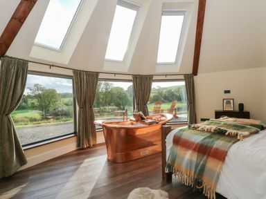 A bedroom with a copper bathtub and large windows at Ty Crwn in Lampeter