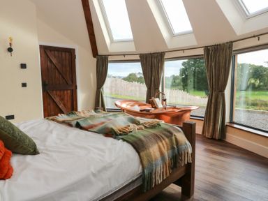 A bedroom with a bed and large windows at Ty Crwn in Lampeter
