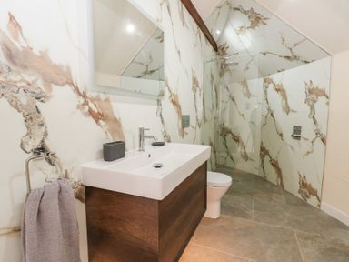 A bathroom with a sink, mirror, toilet, and shower at Ty Crwn in Lampeter