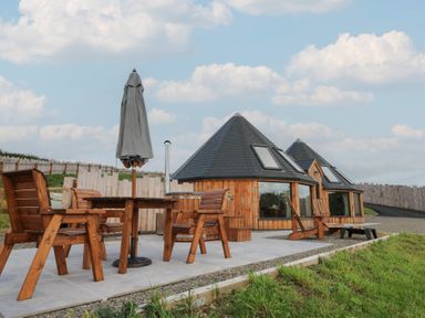 An outdoor area with wooden furniture and an umbrella at Ty Crwn in Lampeter