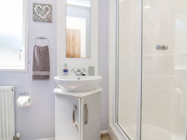 A bathroom with a sink cabinet a mirror a towel rail with a towel a toilet roll holder and a shower at Horizon in Combe Martin