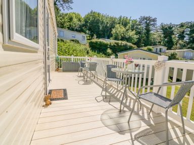 An outdoor deck with two small round tables and four metal chairs with railings and greenery in the background at Horizon Combe Martin
