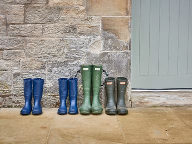 Four pairs of wellington boots lined up outside a stone wall next to a light blue door at The Stallion in Humshaugh